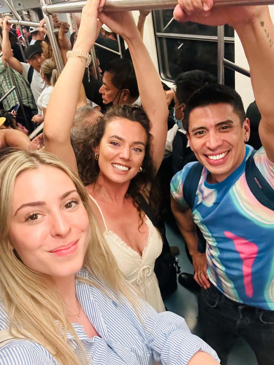 Erik with three friends holding the overhead bars on a crowded Mexico City Metro train,