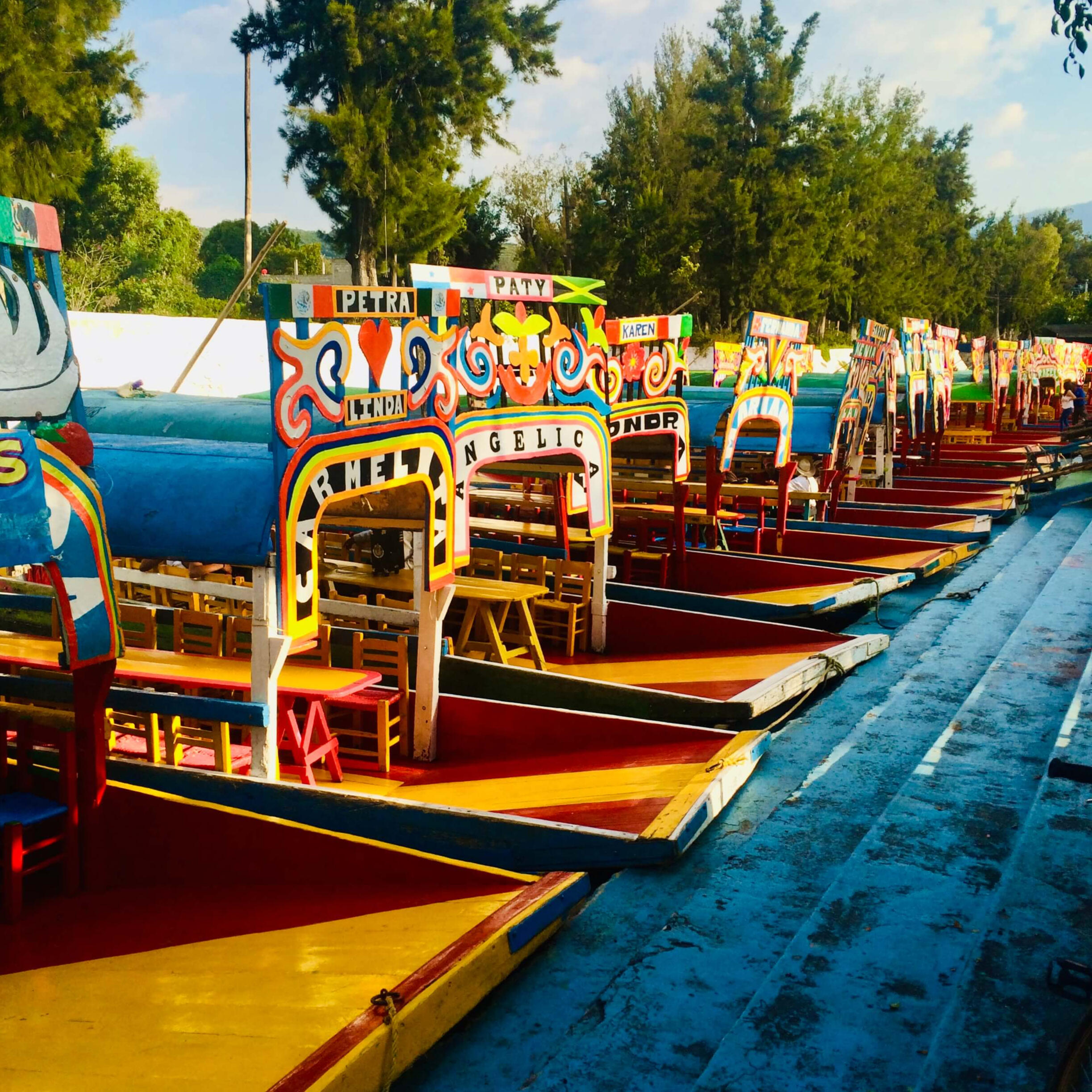 Vibrant traditional colorful trajineras boats floating on the ancient canals of Xochimilco in Mexico City, showcasing a classic cultural and festive experience during our private tours